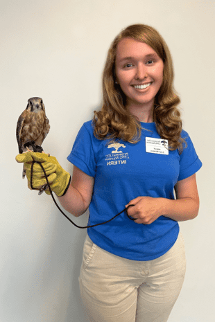 Rising senior Holly Troesch stands in blue, Pittsburgh Zoo & PPG Aquarium shirt and holds a small owl.