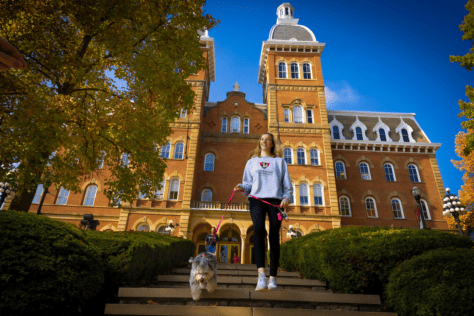 Old Main with female and dog walking through campus